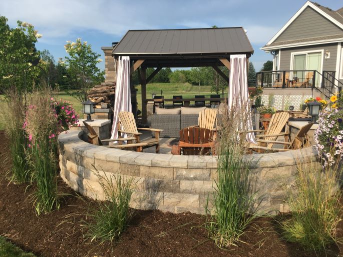 Curved stone patio wall designed and built for residential property near Milwaukee